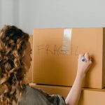 unrecognizable woman writing note on carton box with marker
