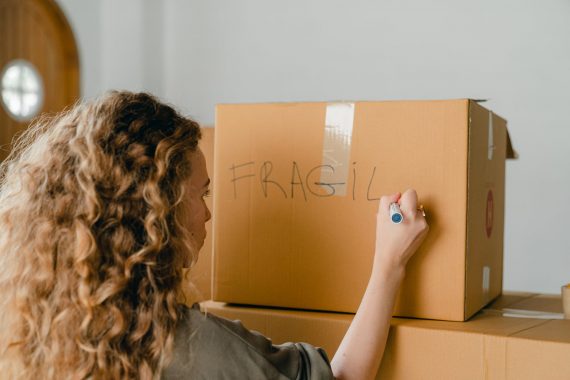 unrecognizable woman writing note on carton box with marker