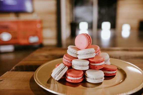 sweet macaroons on round plate on wooden table