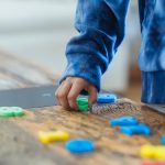 ethnic kid making row of toy numbers