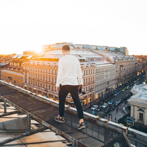 man in white long sleeve shirt and black pants standing on top of a building during