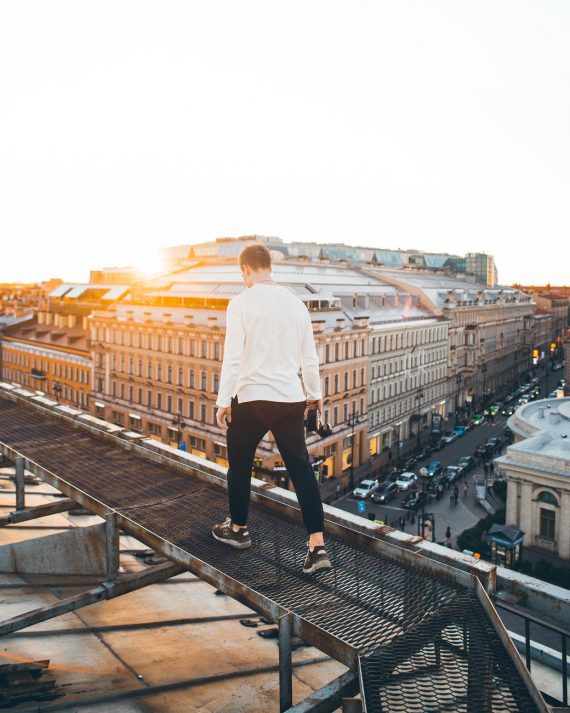 man in white long sleeve shirt and black pants standing on top of a building during