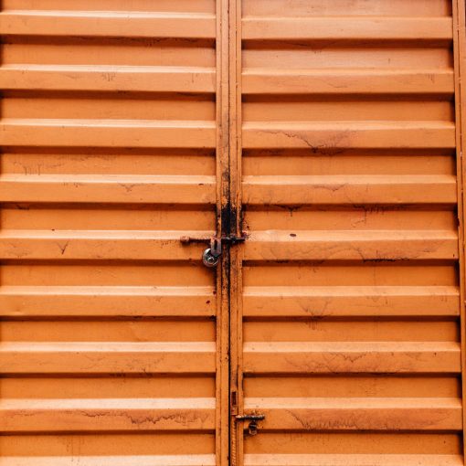 dirty surface of a padlocked orange metal doors