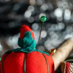 close up shot of a red pincushion beside a thimble