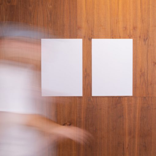 unrecognizable person walking near wall with empty papers