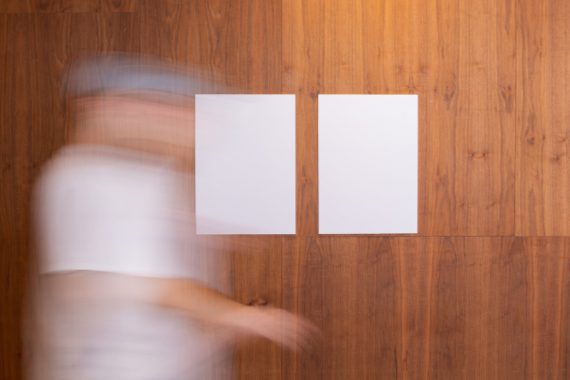 unrecognizable person walking near wall with empty papers