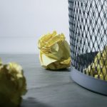 focus photo of yellow paper near trash can