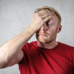 a man in red shirt covering his face