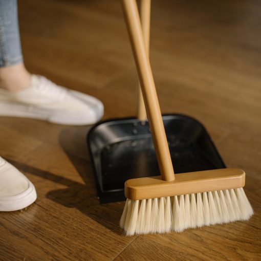 person wearing white pants and white socks standing beside brown broom