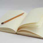 white notebook and yellow pencil