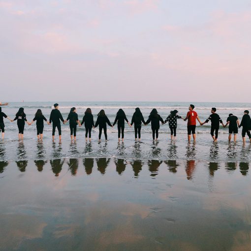 team holding their hands on seashore