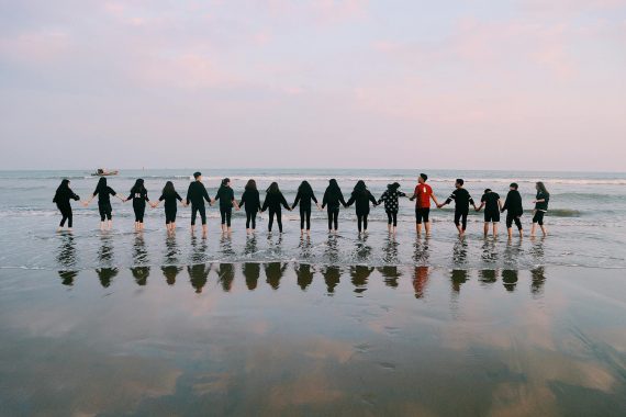 team holding their hands on seashore