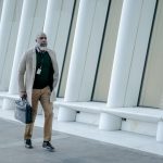 man in corporate attire holding a black handbag