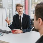 man sitting at desk in office consulting client