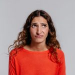 woman in red crew neck shirt making facial expression