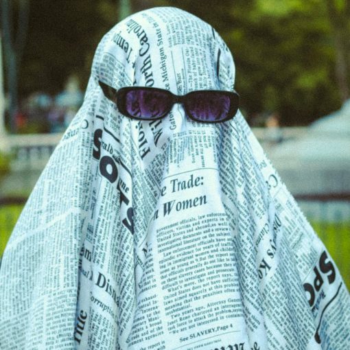 portrait of person in ghost costume from newspapers and in sunglasses