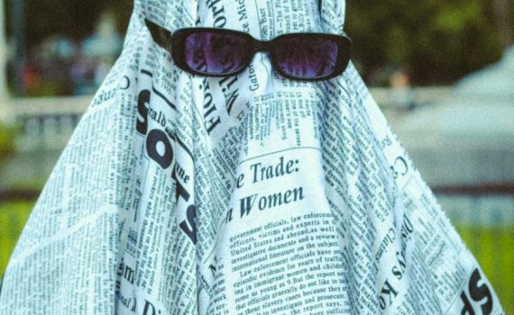 portrait of person in ghost costume from newspapers and in sunglasses