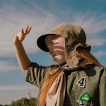 girl scout standing outside and blocking the sun from her face with her hand