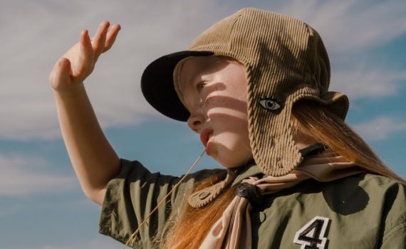 girl scout standing outside and blocking the sun from her face with her hand