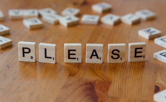 A close up of a wooden block spelling please